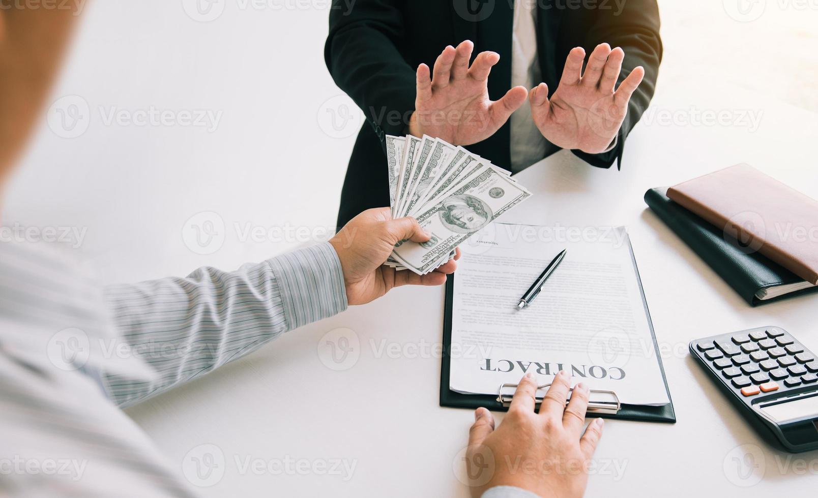 Businessperson refusing bribe given money by partner with anti bribery corruption concept. photo