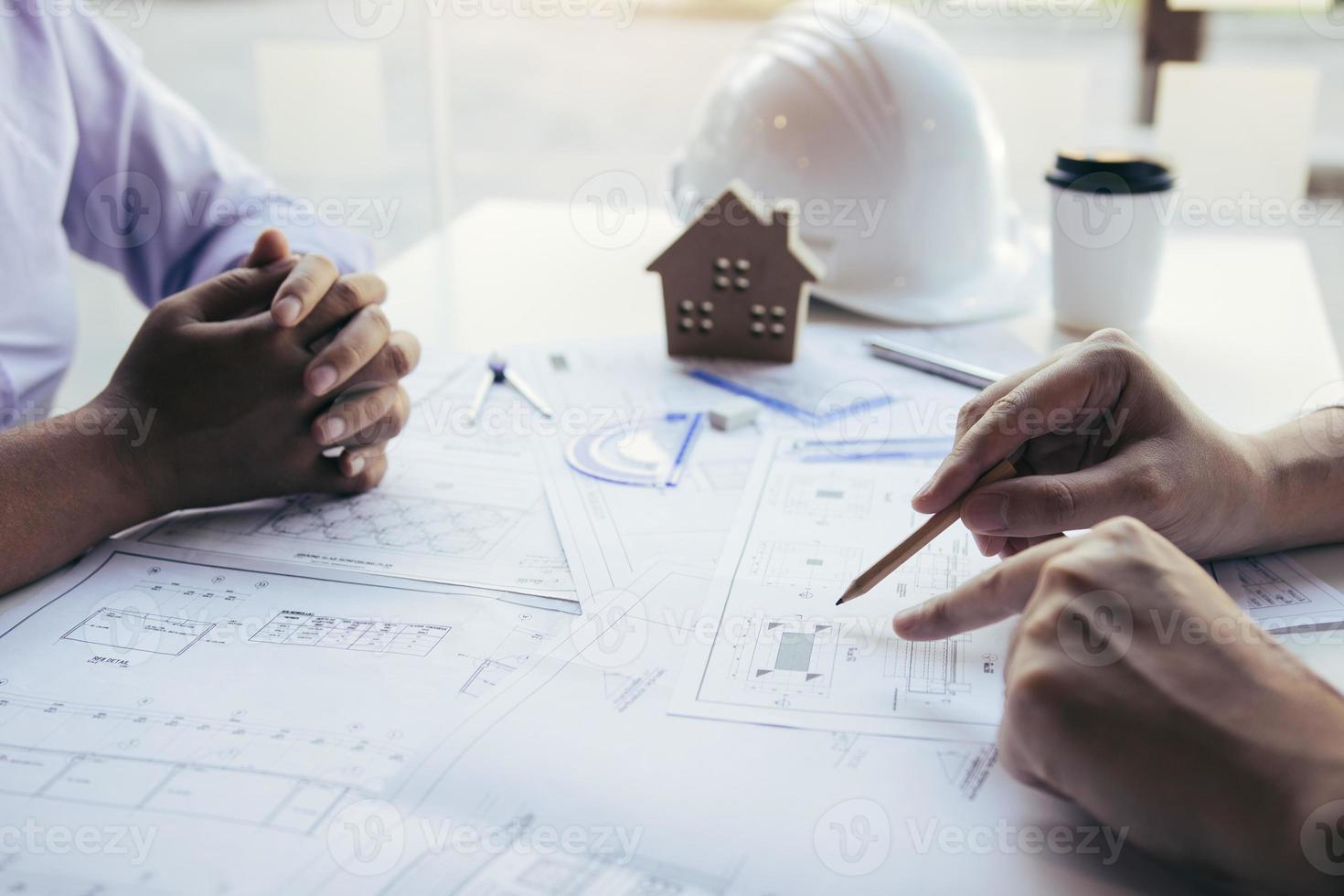 Architects engineer working with blueprints on table and discussing project together at the meeting in the office. photo