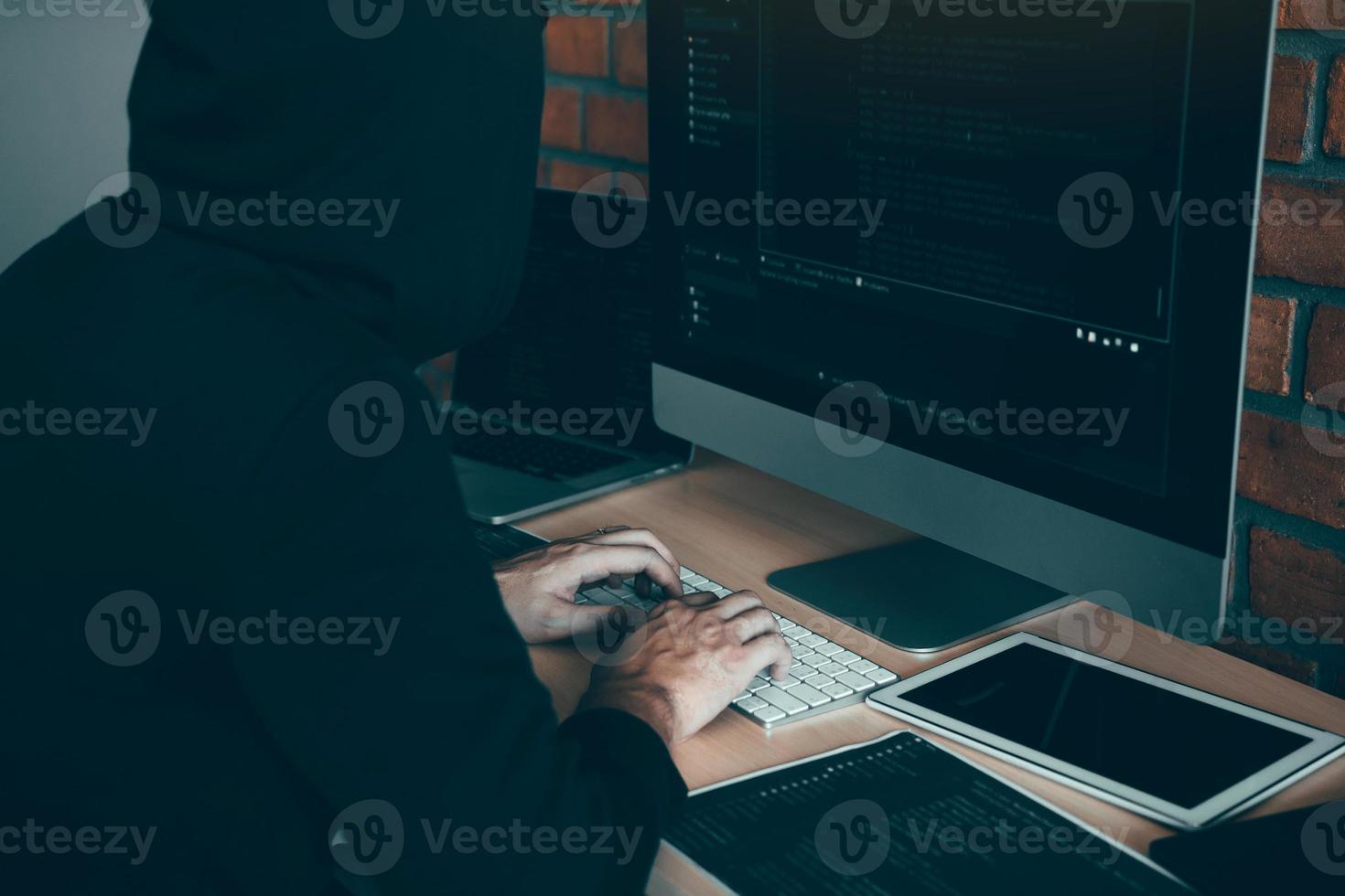 Hacker in the hood working with computer with hacking breaking into data servers. photo