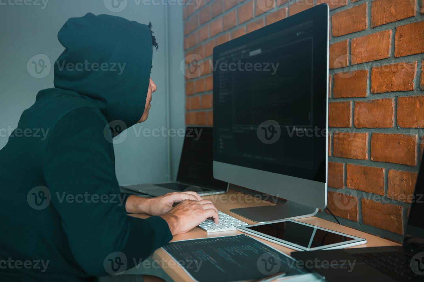 Hacker in the hood working with computer with hacking breaking into data servers. photo