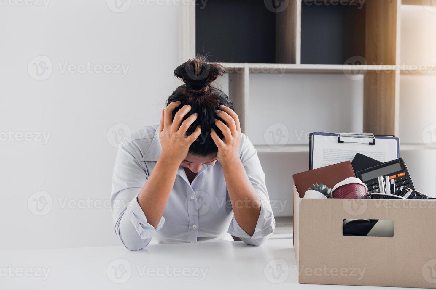 Woman employee used his hand to hold the head feeling sad at his desk when he received the contract envelope for resigning from the company. photo