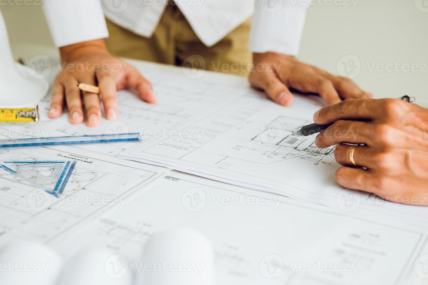 Two partnership architects or engineering working with blueprints and discussing project together at the meeting in the office. photo