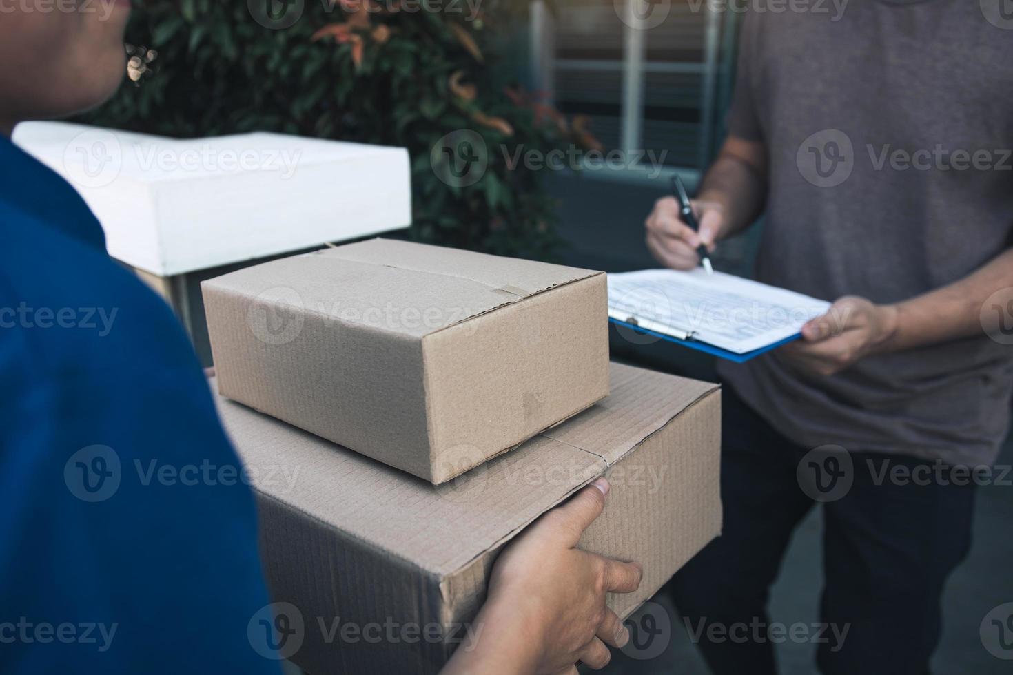 repartidor parado en la puerta de casa y llevando paquetes para que los jóvenes los firmen. foto