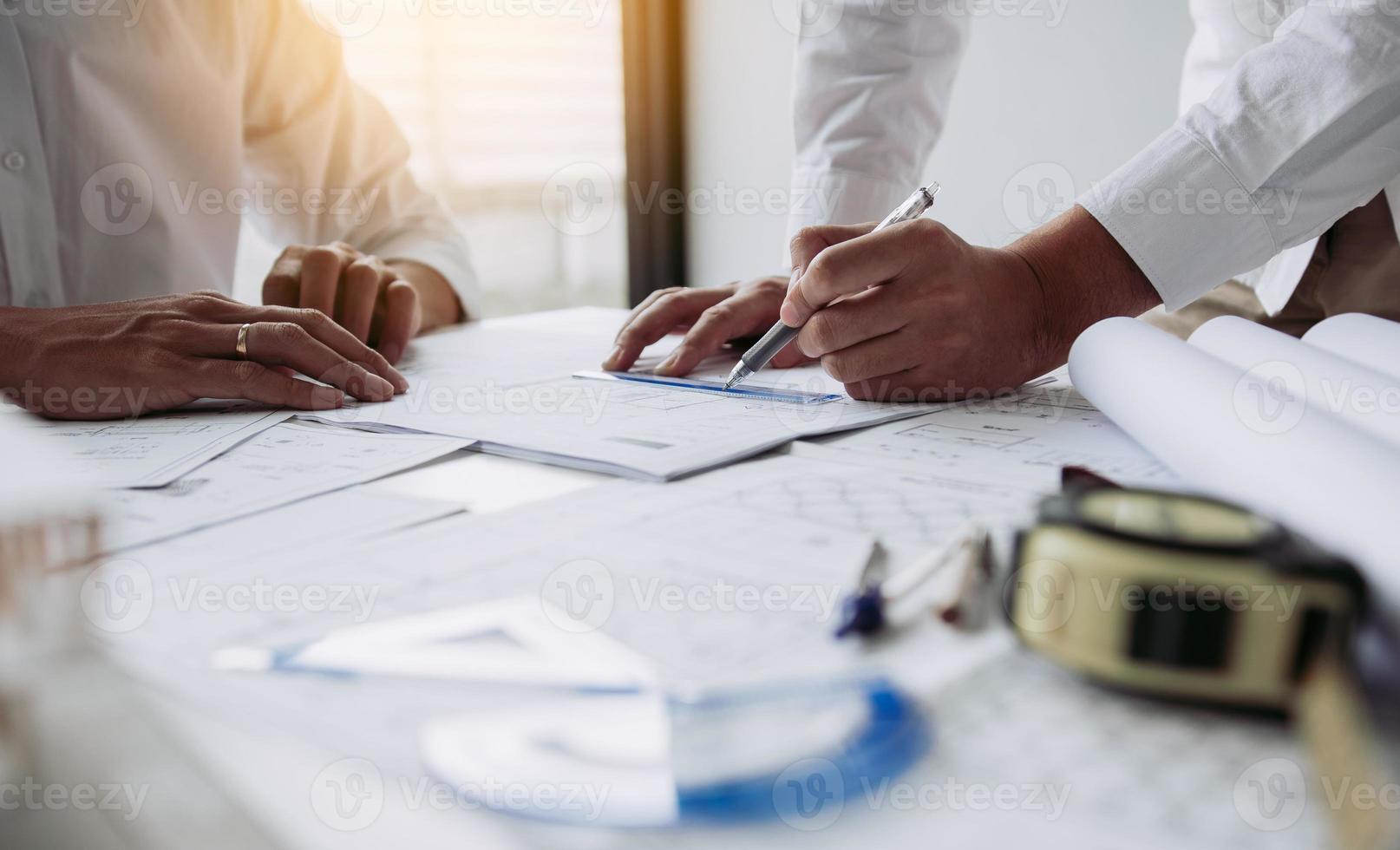 Architects engineer working with blueprints on table and discussing project together at the meeting in the office. photo