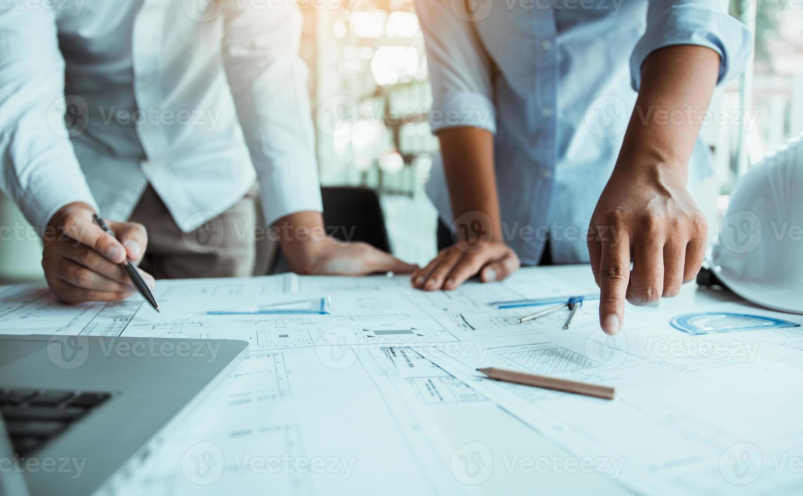 Two architect working at construction site and compass drawing pointing on blueprint with partnership. photo