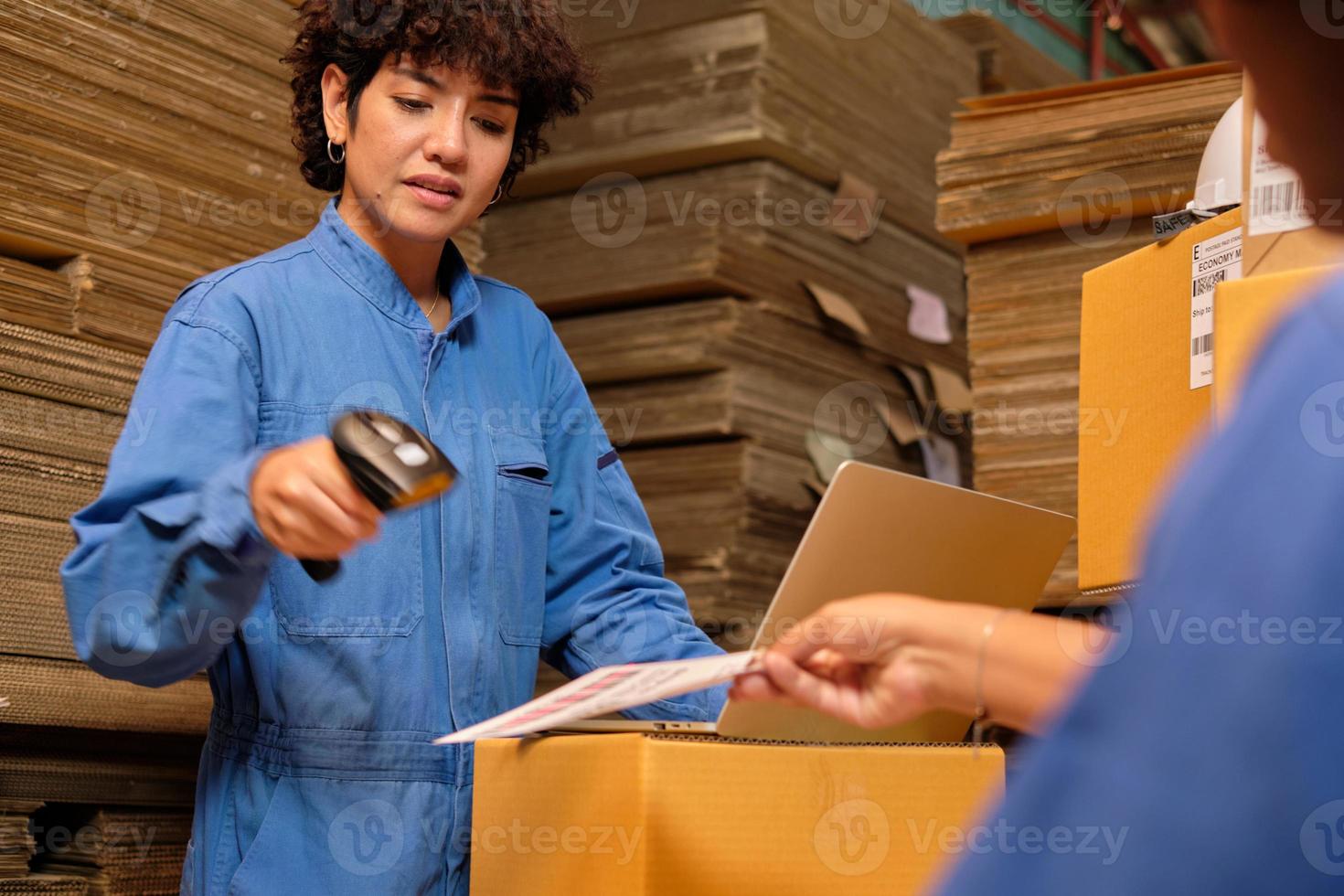 Two safety uniform female workers and colleagues use bar code scanner to check shipment orders stock at parcels warehouse, paper manufacture factory for packing industry, logistic transport service. photo