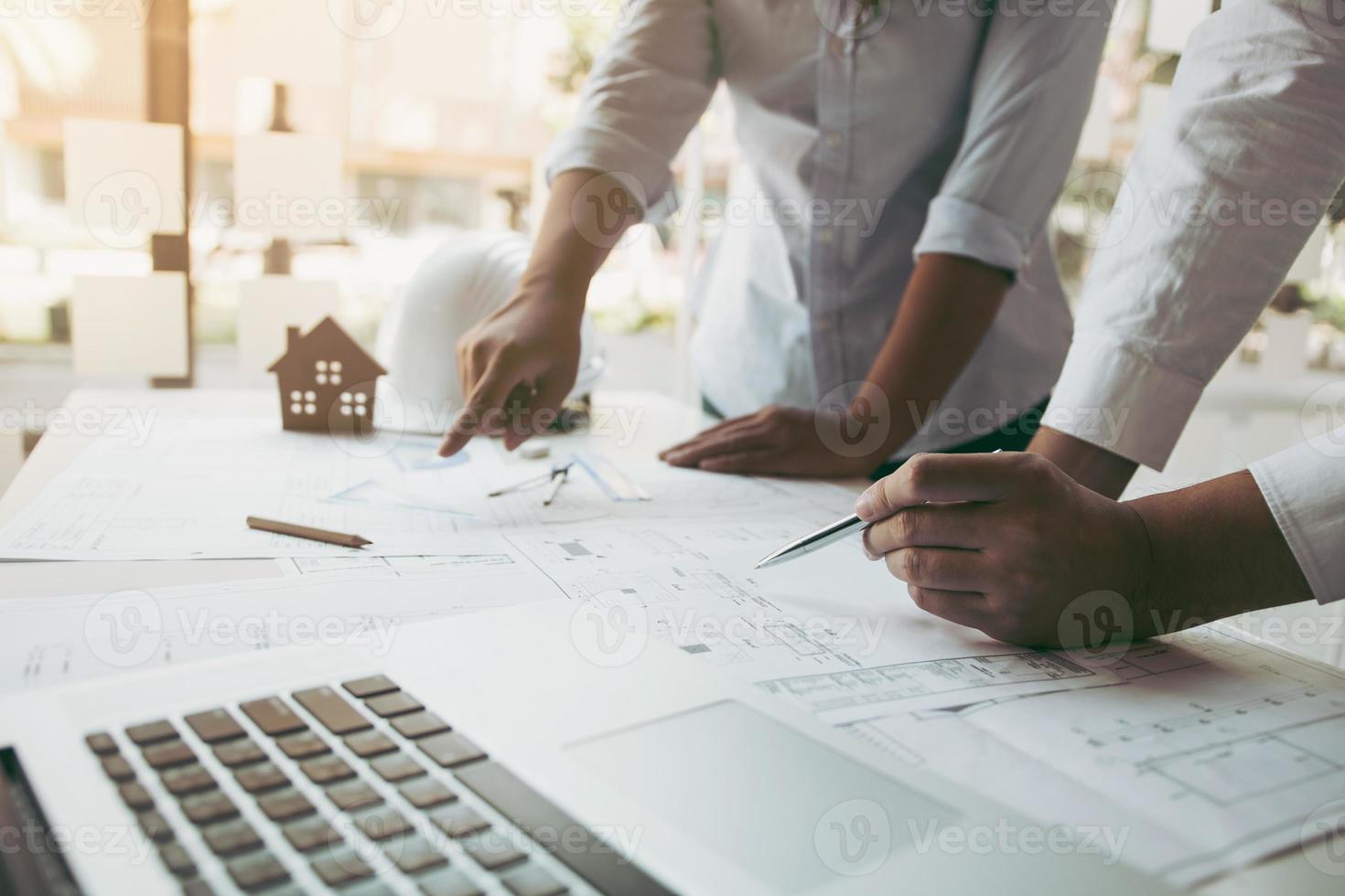 Two architect working at construction site and compass drawing pointing on blueprint with partnership. photo