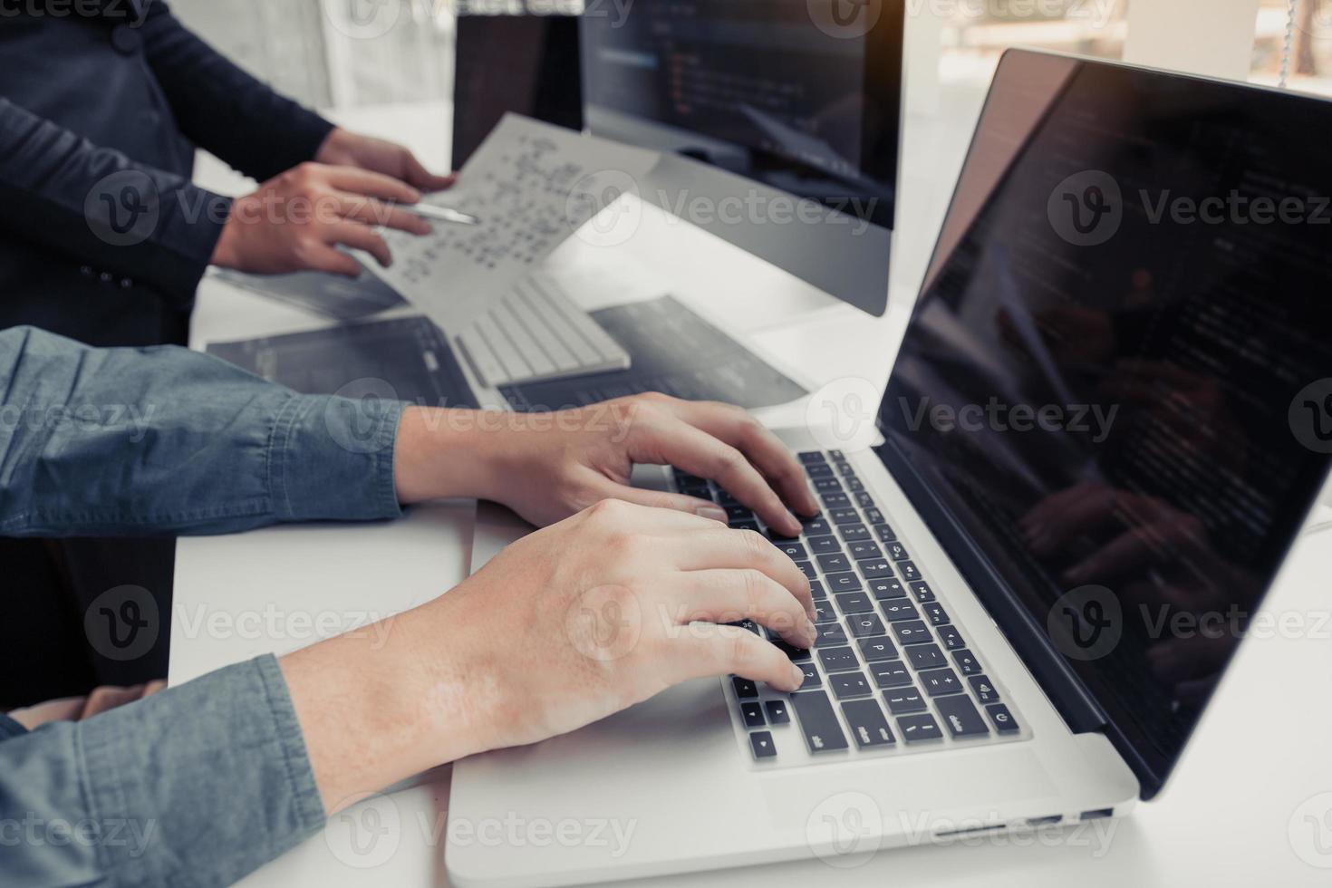 Two partnerships developing programming and coding technologies working on laptop and analyzing together. photo