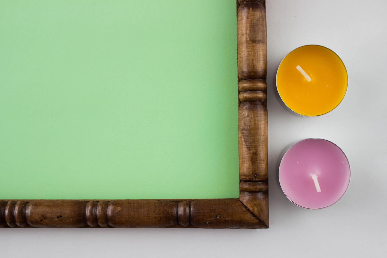 Part of wooden carved frame with a green background inside decorated with candles. photo