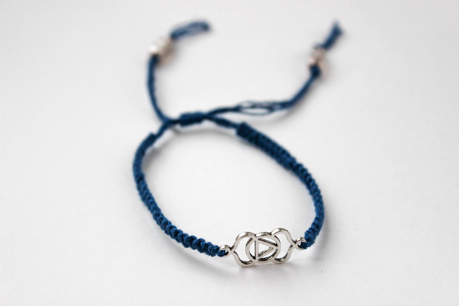 Brazalete trenzado azul con chakra ajna sobre fondo blanco. foto