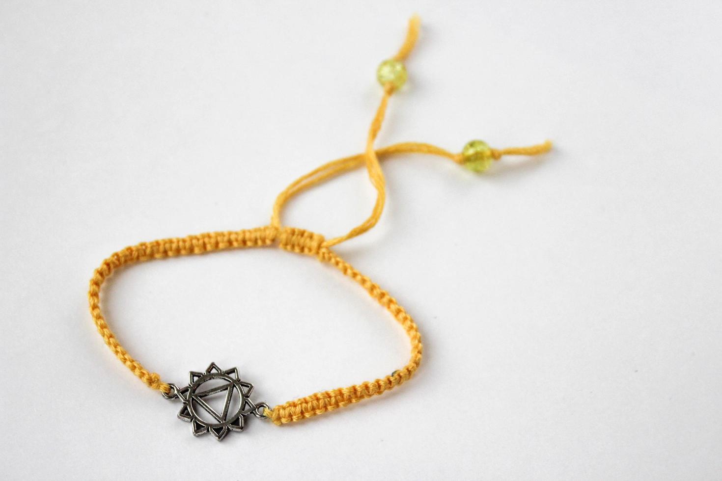 yellow braded bracelet with chakra manipura on white background photo