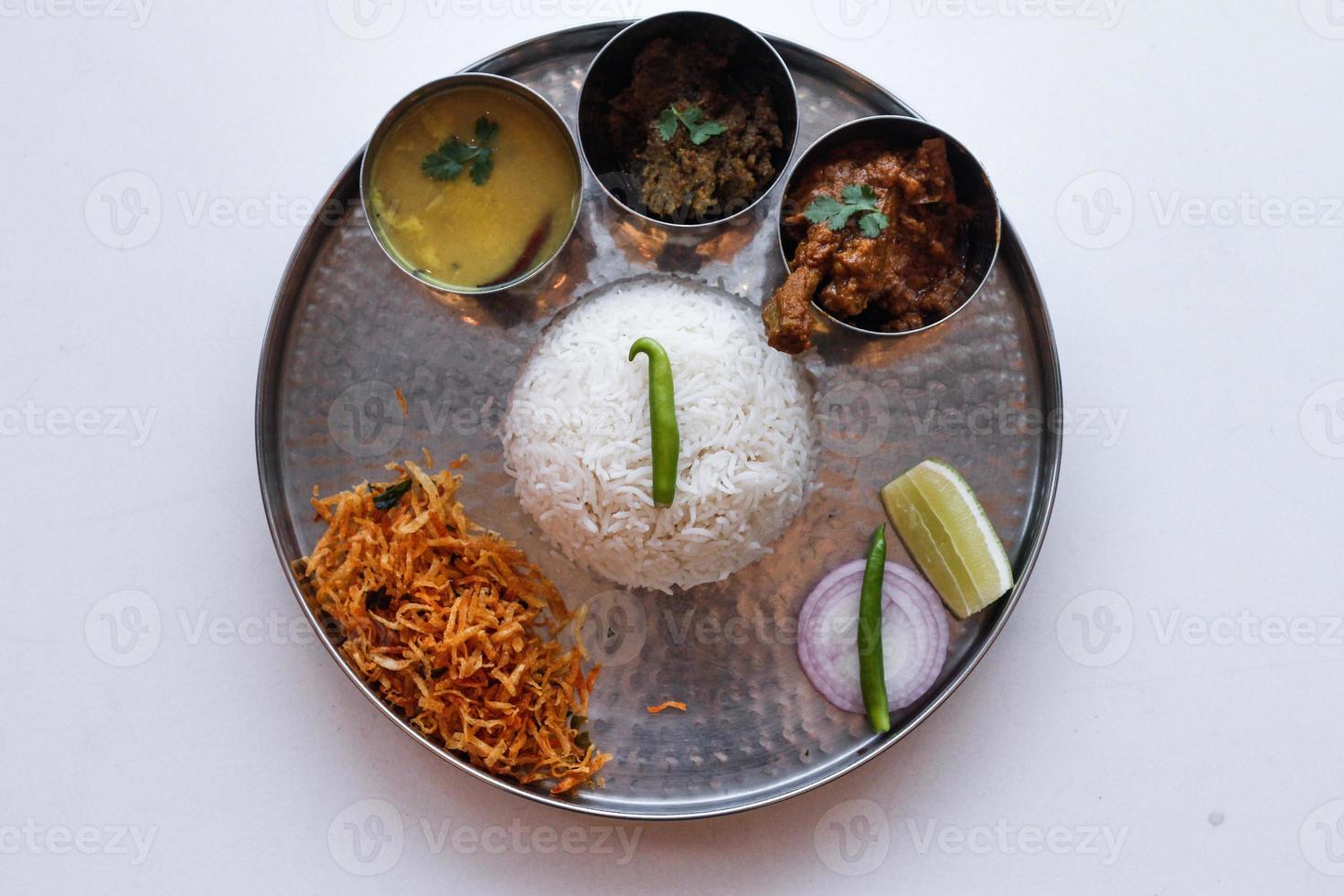 Indian Thali is a platter served on a plate with various dishes, rice,Fish, alu baja,Dal photo