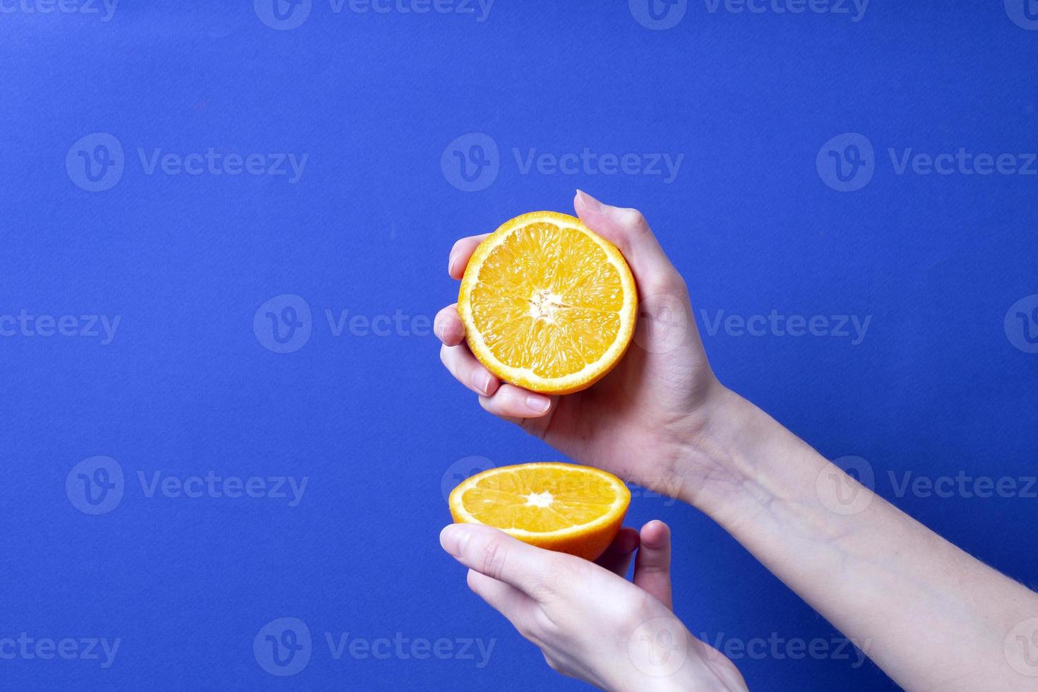 mano de mujer sosteniendo una naranja madura cortada foto