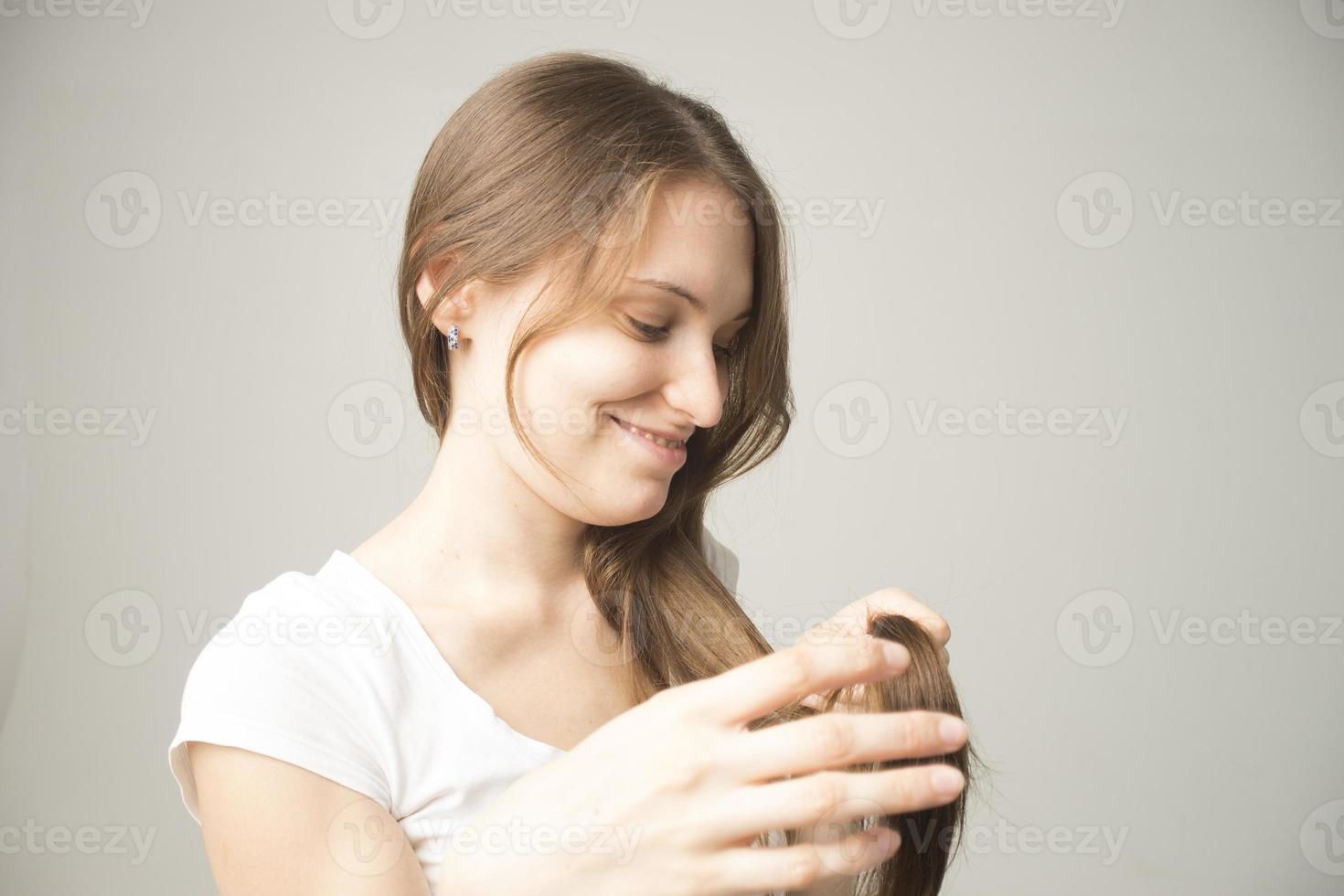 girl on a gray background holds a hair in her hand photo
