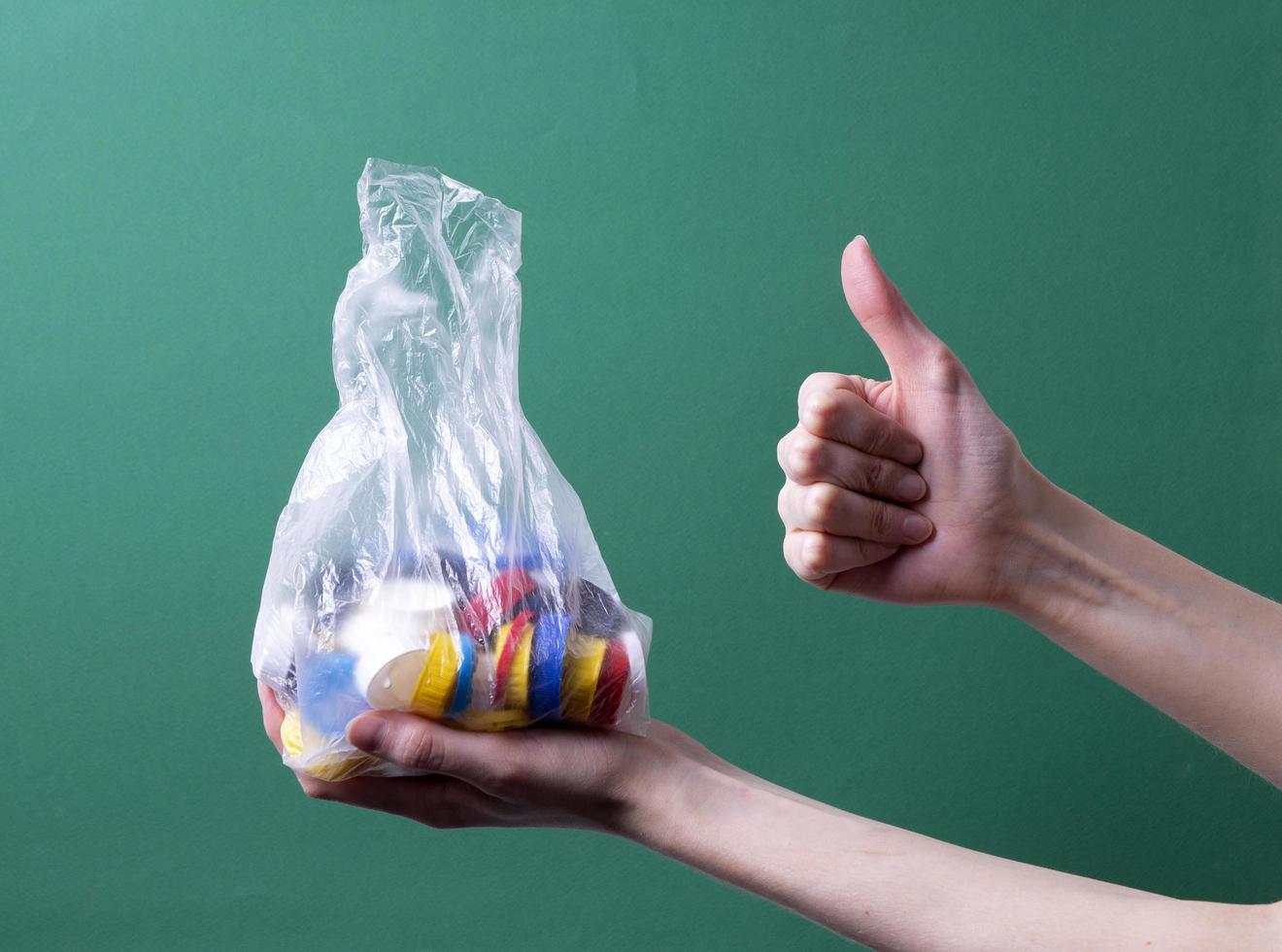 a woman's hand holds a bag with plastic lids for recycling photo