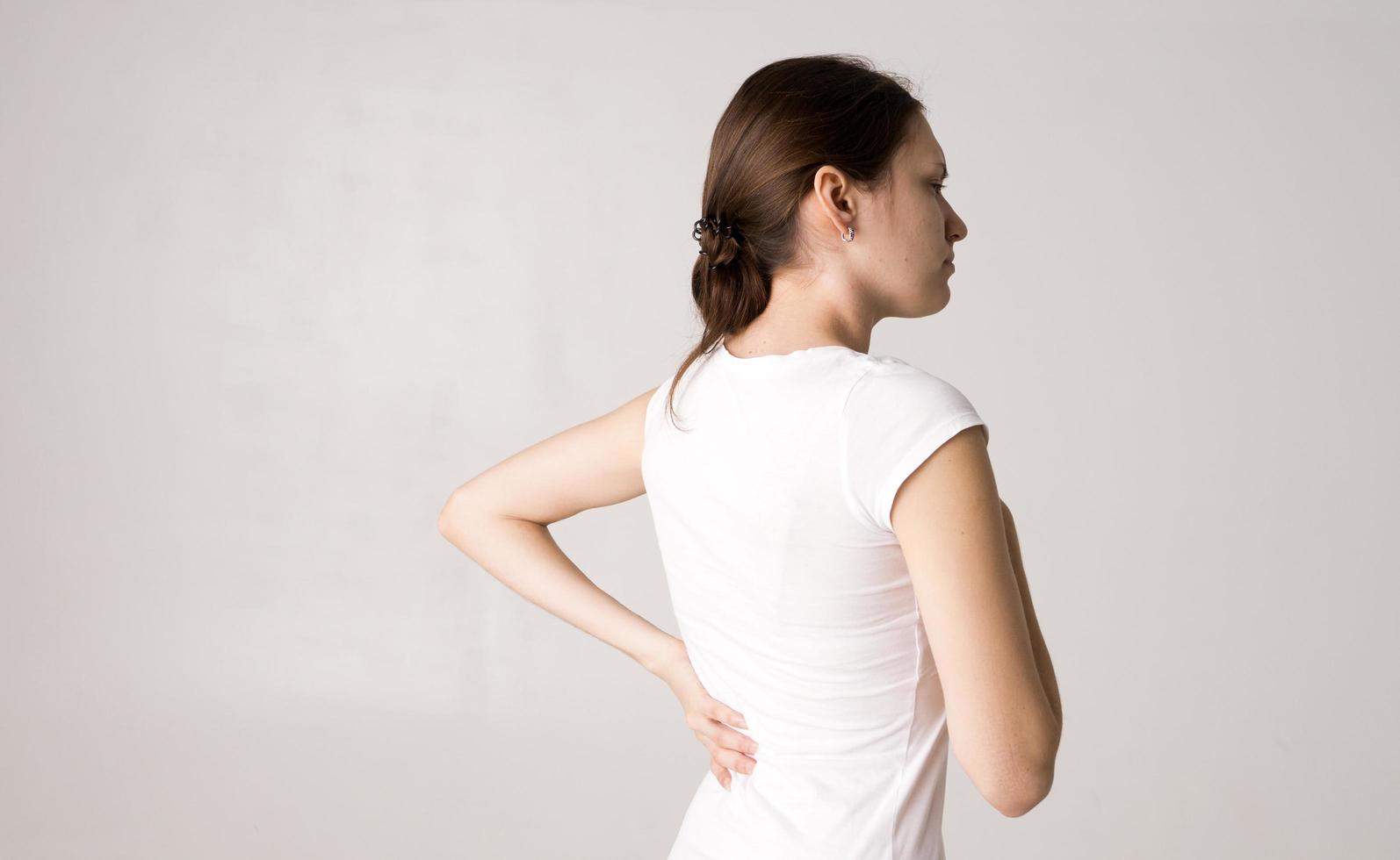 Attractive teenage girl suffers from backache. All on white background photo