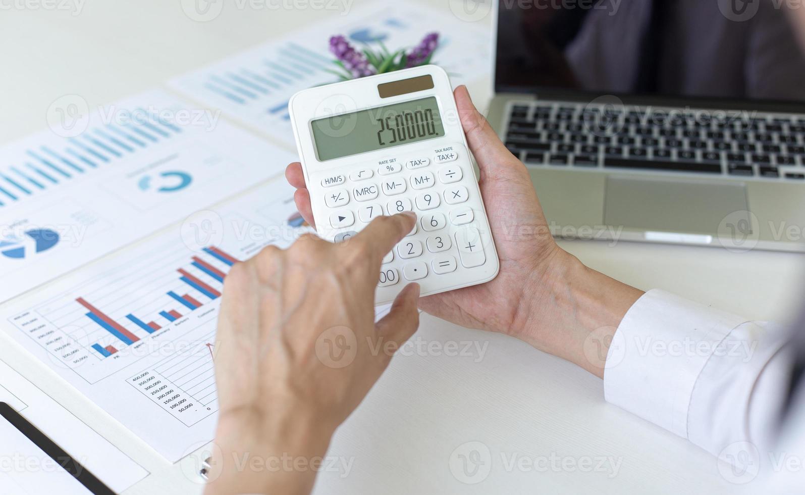 Accounting businessmen are calculating income-expenditure and analyzing real estate investment data, She works on a desk has graphs and calculators with laptop, Financial and tax systems concept. photo