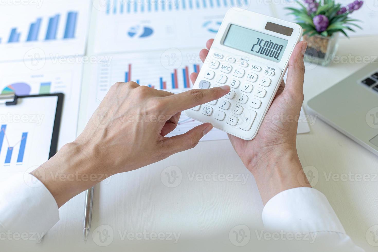 Accounting businessmen are calculating income-expenditure and analyzing real estate investment data, She works on a desk has graphs and calculators with laptop, Financial and tax systems concept. photo