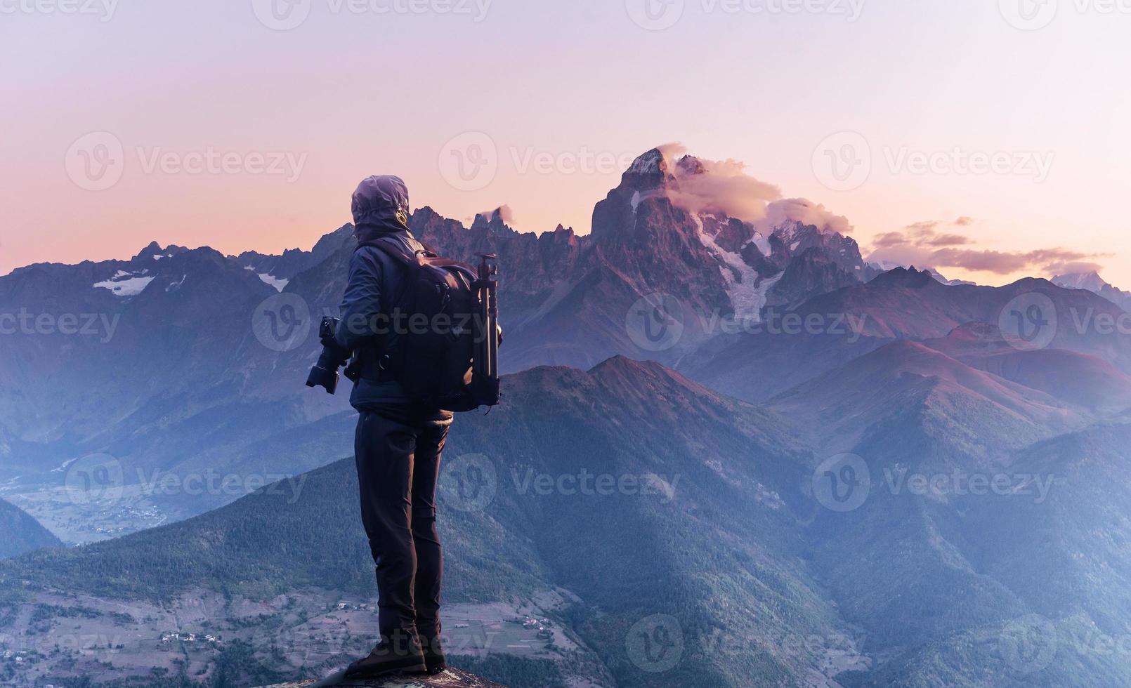 Professional photographer takes photos with big camera on peak of rock