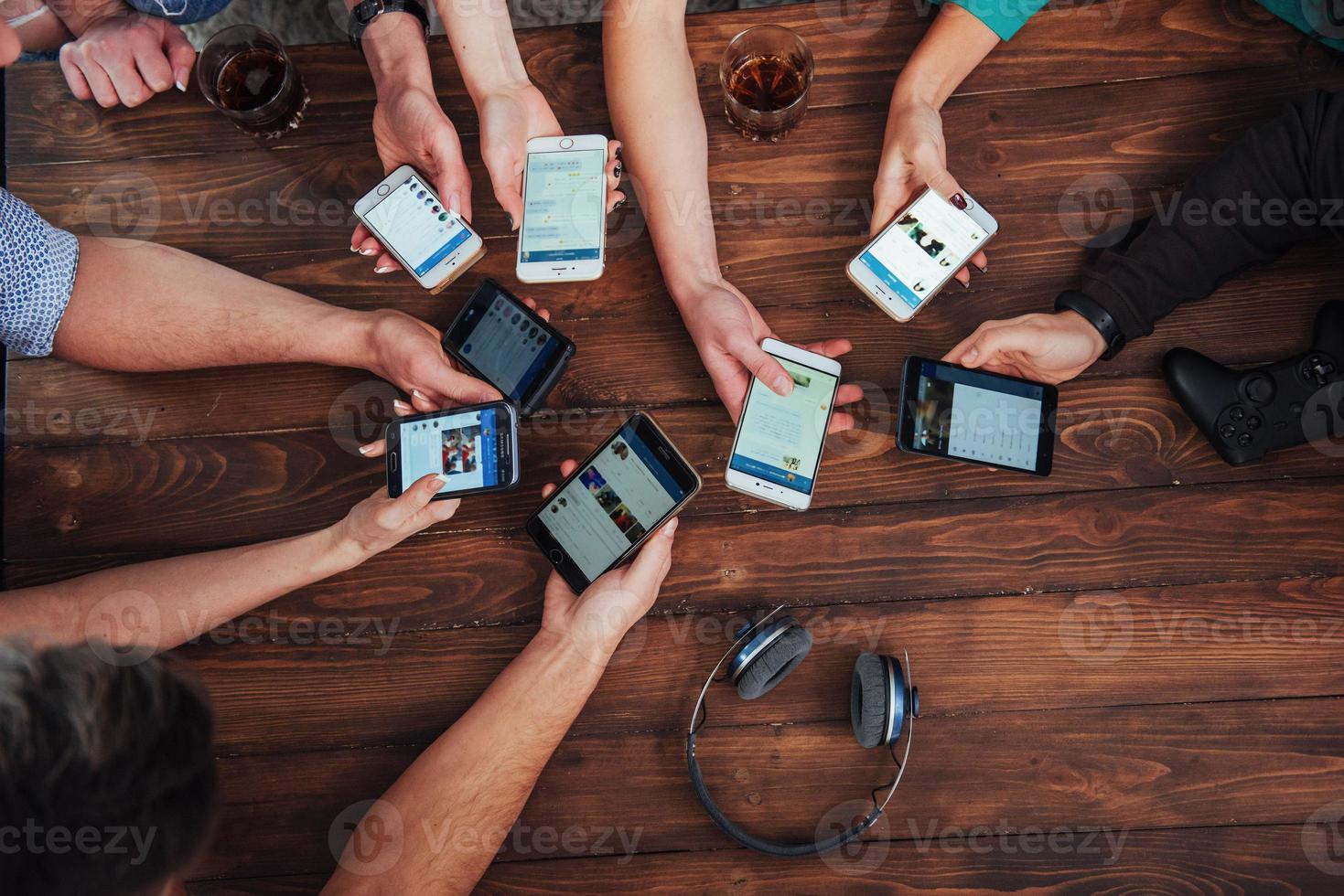 Top view hands circle using phone in cafe - Multiracial friends mobile addicted interior scene from above - Wifi connected people in bar table meeting - Concept of teamwork photo