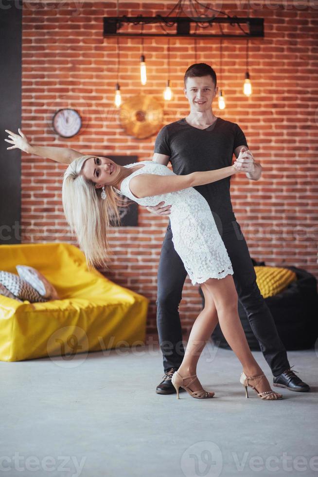 pareja joven bailando música latina. bachata, merengue, salsa. pose de dos elegancia en el café con paredes de ladrillo foto