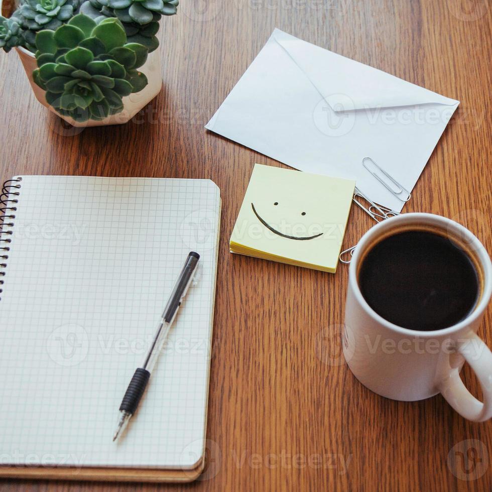 bloc de notas y bolígrafo junto a una taza de café en una mesa de madera al aire libre en un café. foto