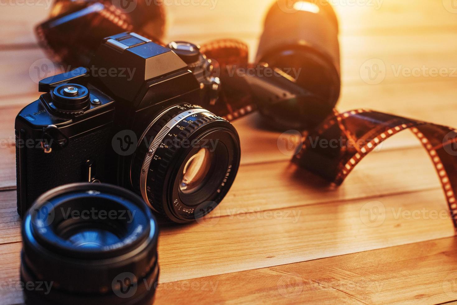 Old film camera and a roll of  on wood photo