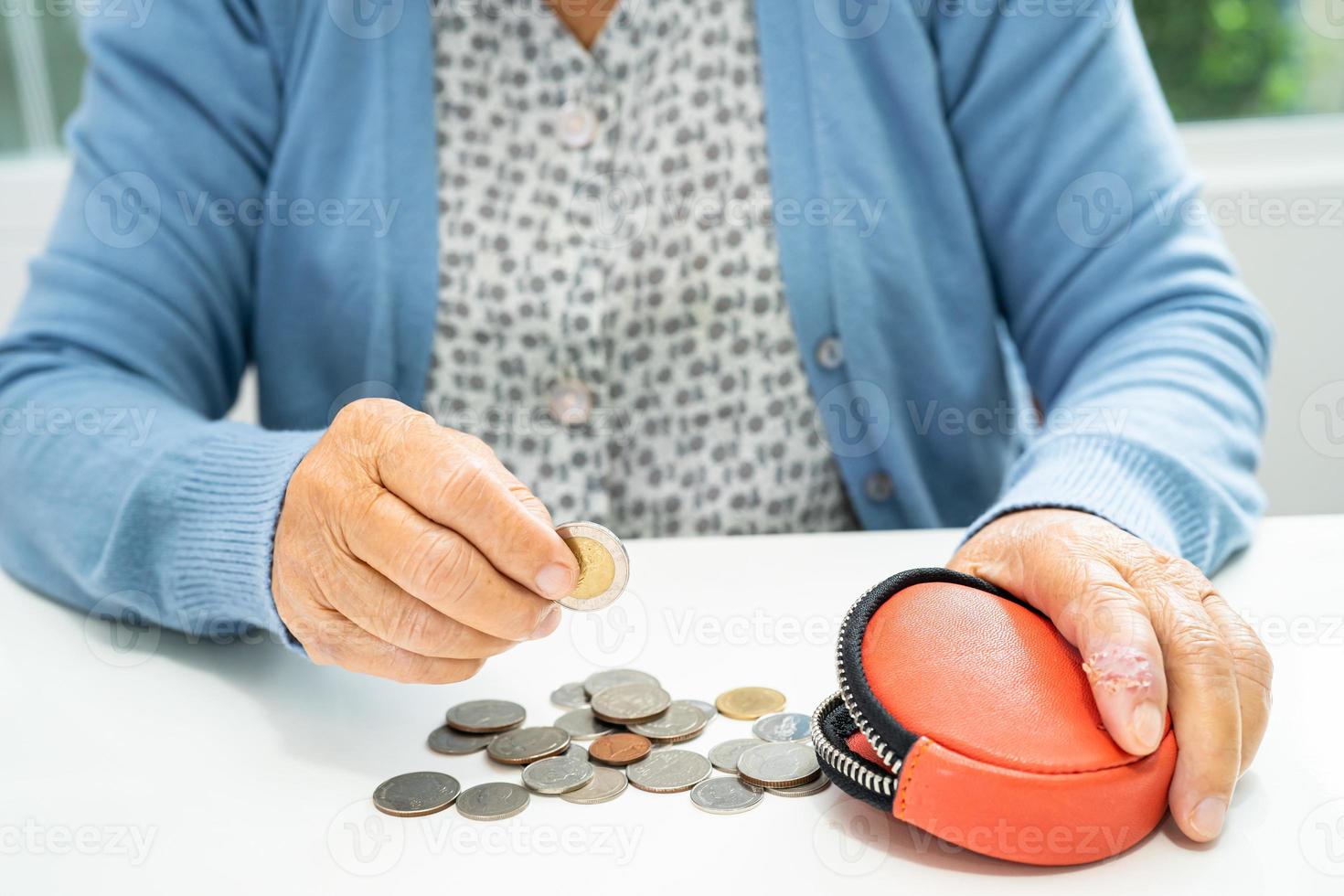 anciana asiática mayor o anciana sosteniendo contando dinero de moneda en el bolso. pobreza, problema de ahorro en la jubilación. foto