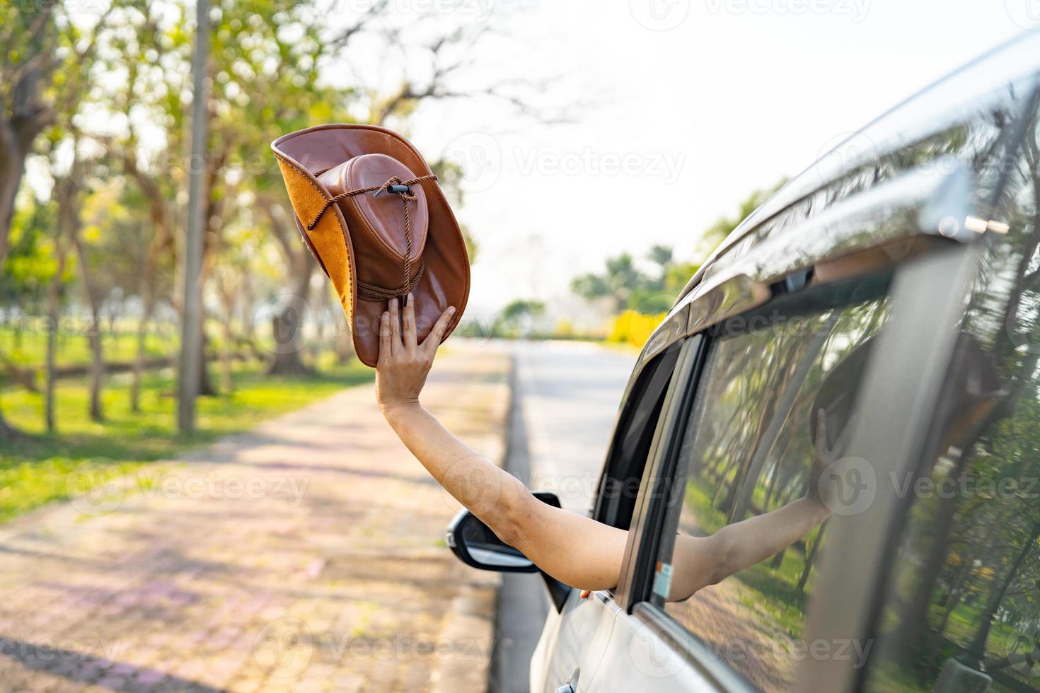 Happy enjoy and freedom in traveling trip with raised hand and holding cowboy hat outside of window car in summer vacation holiday photo