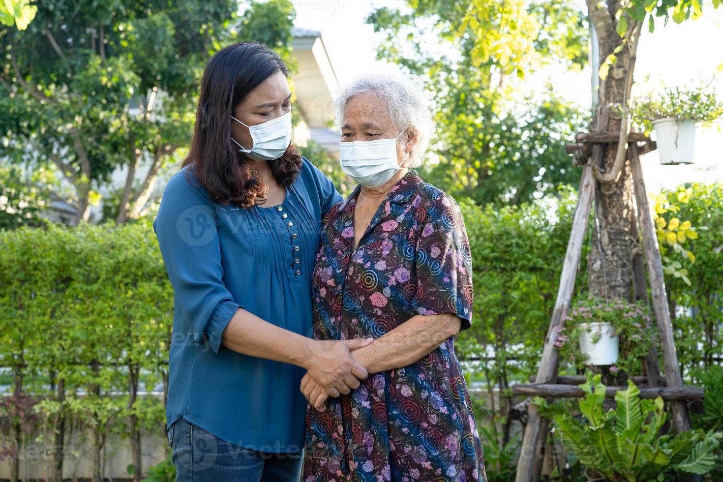 Caregiver help Asian elderly woman while walking with happy in nature park. photo