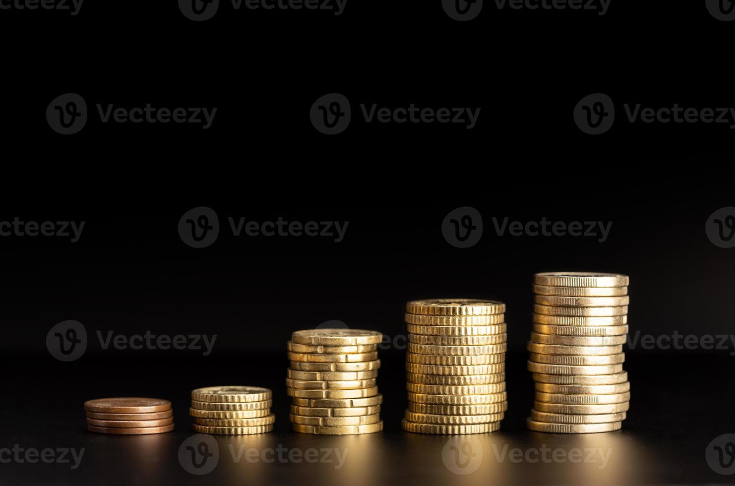 Rising Coin stacks on black background. Growth, income, savings concept. Copy space photo