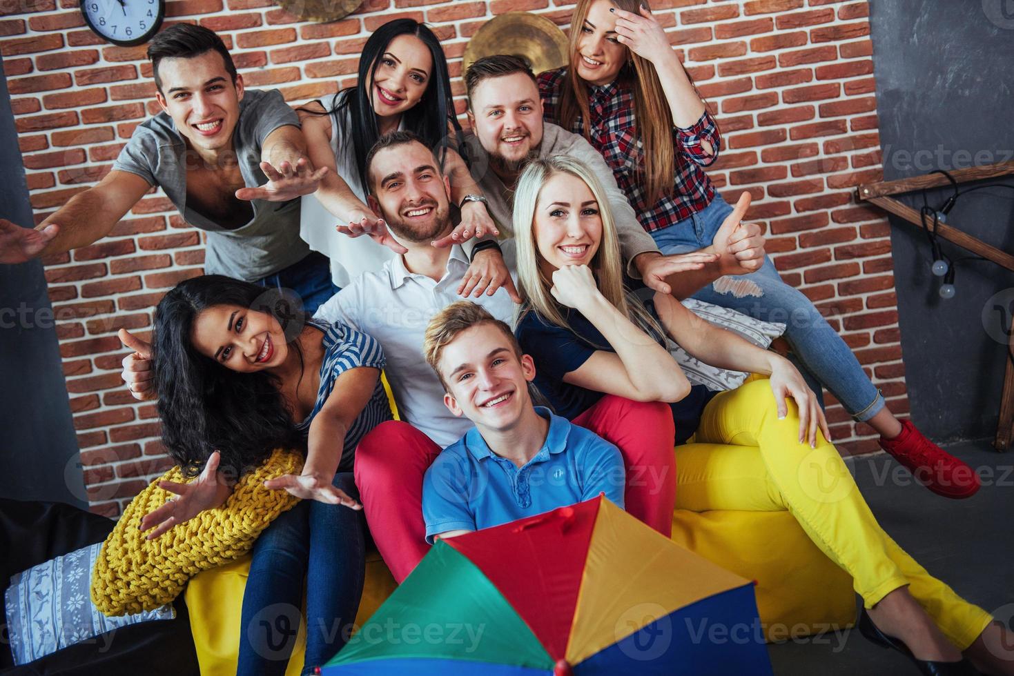 Group portrait of multi-ethnic boys and girls with colorful fashionable clothes holding friend posing on a brick wall, Urban style people having fun, Concepts about youth togetherness lifestyle photo