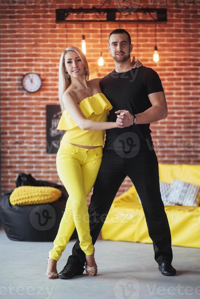 Young couple dancing latin music Bachata, merengue, salsa. Two elegance pose on cafe with brick walls photo