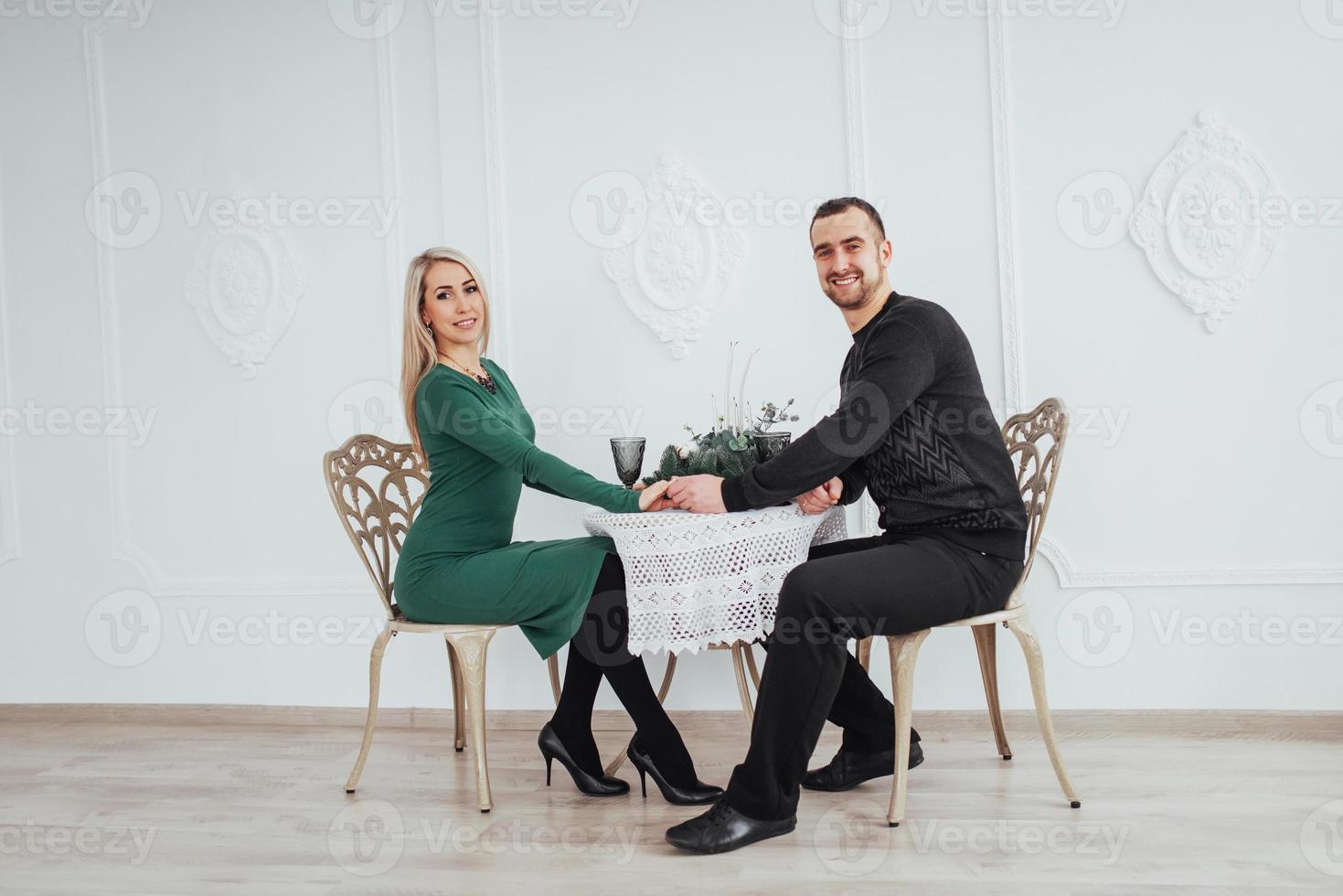 encanta sentarse en la mesa pareja hombre y mujer con copas de vino sobre fondo blanco en el restaurante. cena de san valentin foto