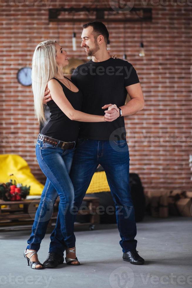 pareja joven bailando música latina bachata, merengue, salsa. pose de dos elegancia en el café con paredes de ladrillo foto