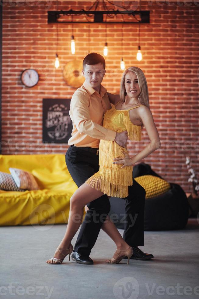 pareja joven bailando música latina. bachata, merengue, salsa. pose de dos elegancia en el café con paredes de ladrillo foto