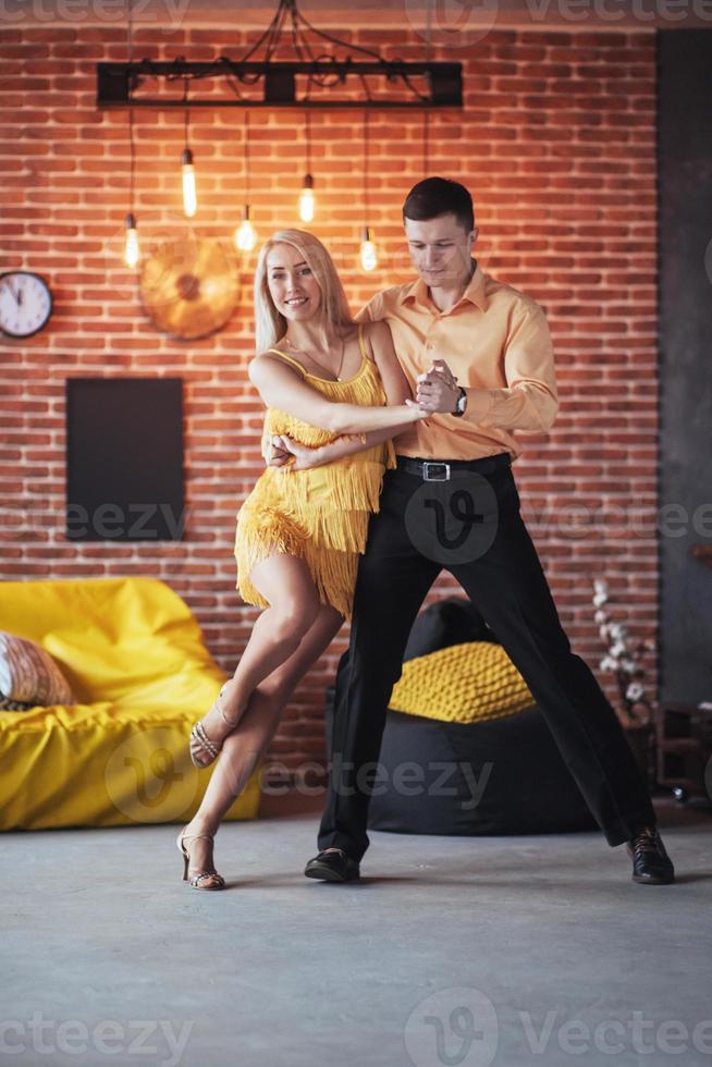 Young couple dancing latin music. Bachata, merengue, salsa. Two elegance pose on cafe with brick walls photo