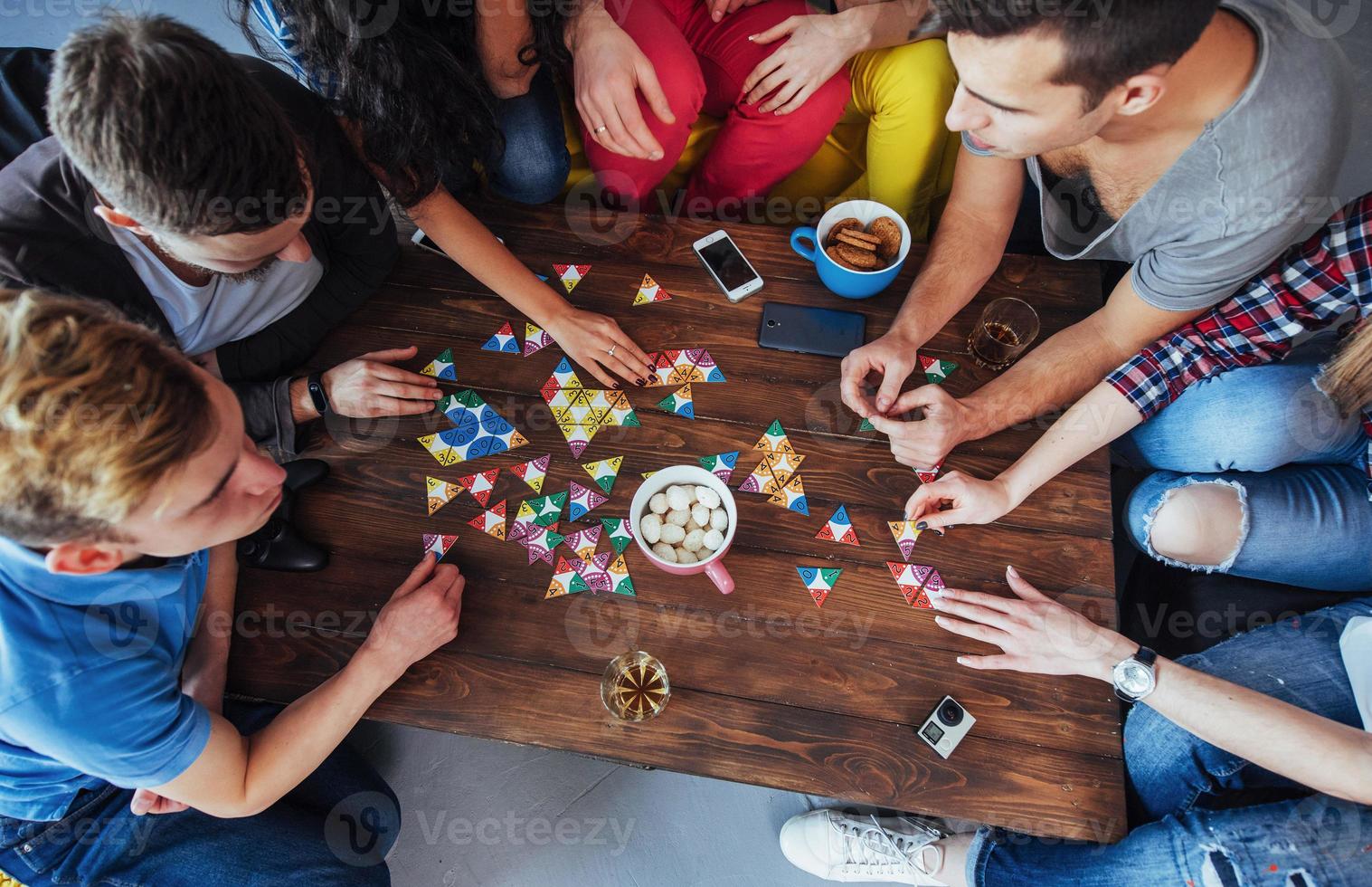 vista superior foto creativa de amigos sentados en una mesa de madera. divertirte mientras juegas al juego de mesa