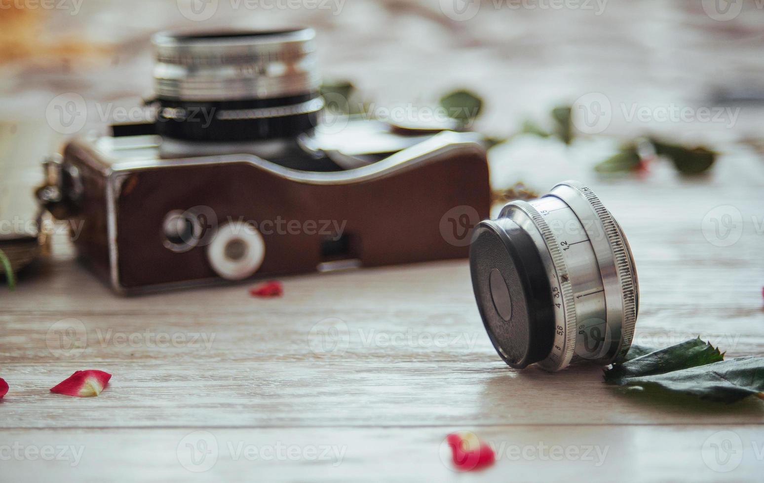 rollo de cámara retro película fotográfica y flores sobre fondo blanco de madera foto