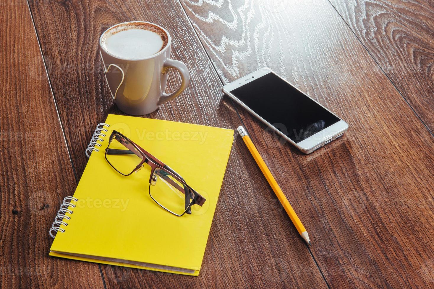 On wooden background notebook pencil, coffee and flowers. photo