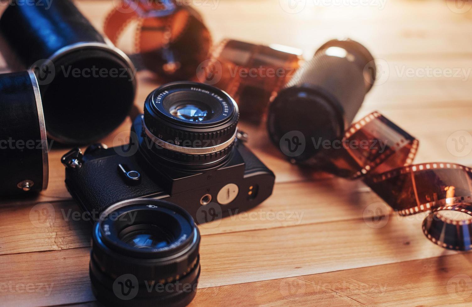 Old film camera and a roll of  on wood photo