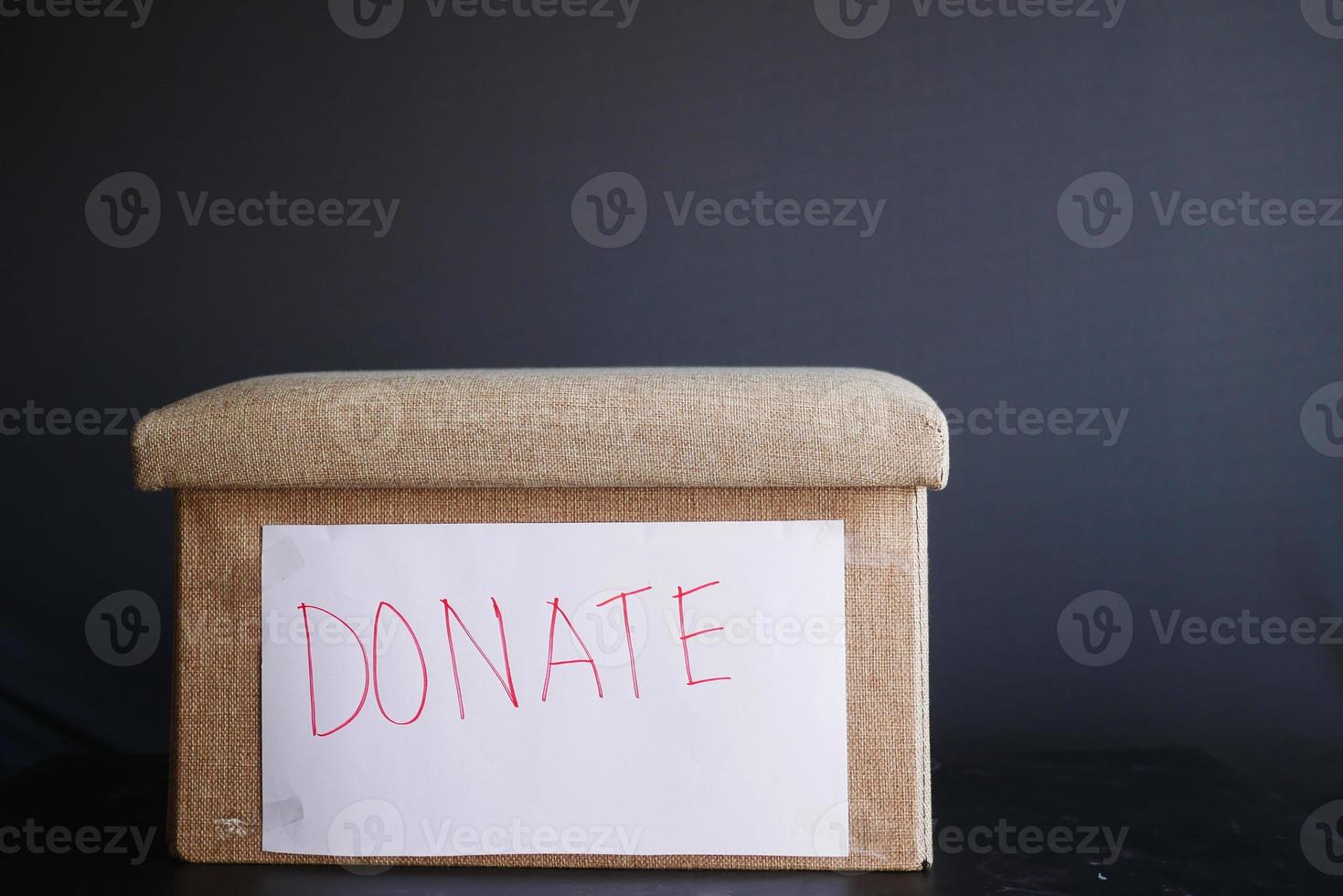 Donation box on table against black background photo