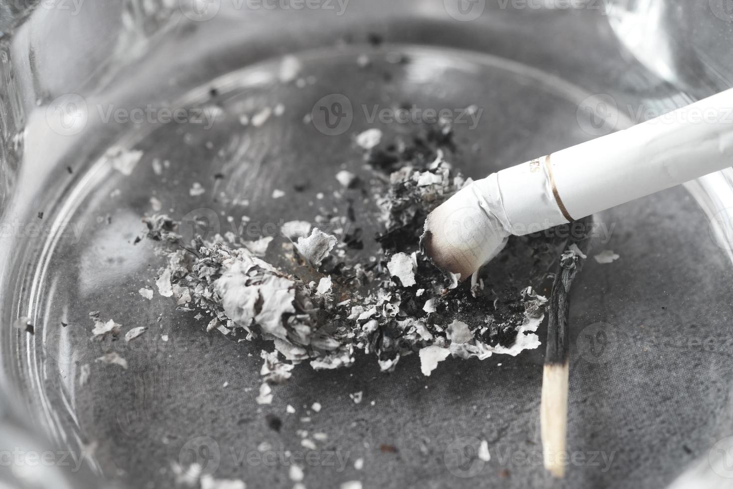 Close up burning cigarette in ashtray on table photo