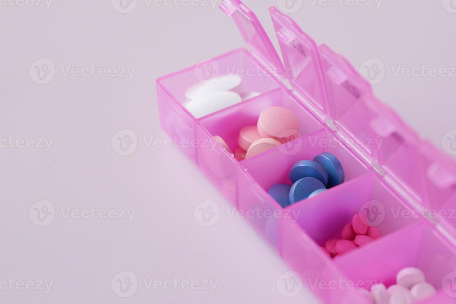 píldoras médicas en una caja de pastillas sobre fondo violeta claro foto