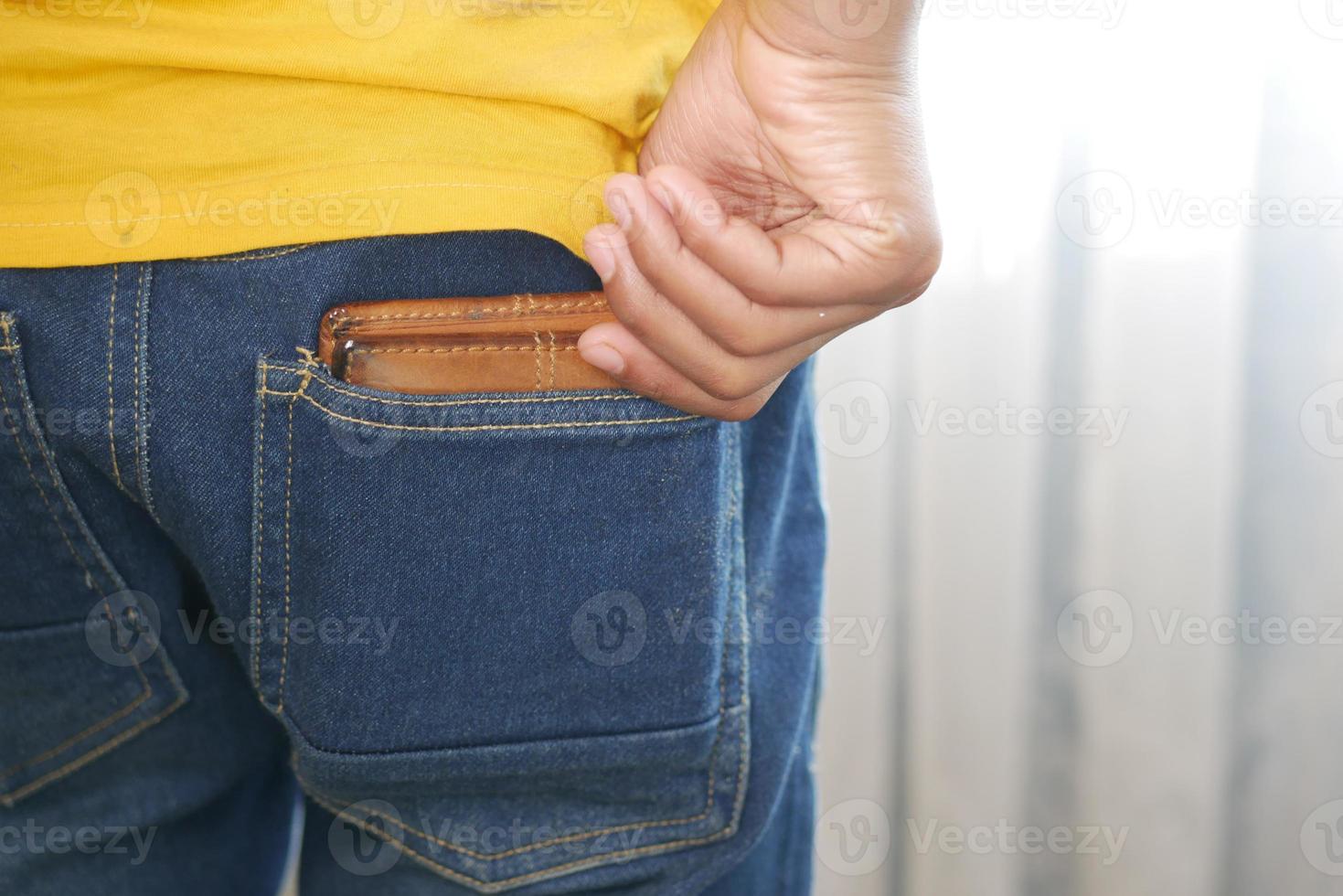 joven sacando la billetera del bolsillo trasero foto