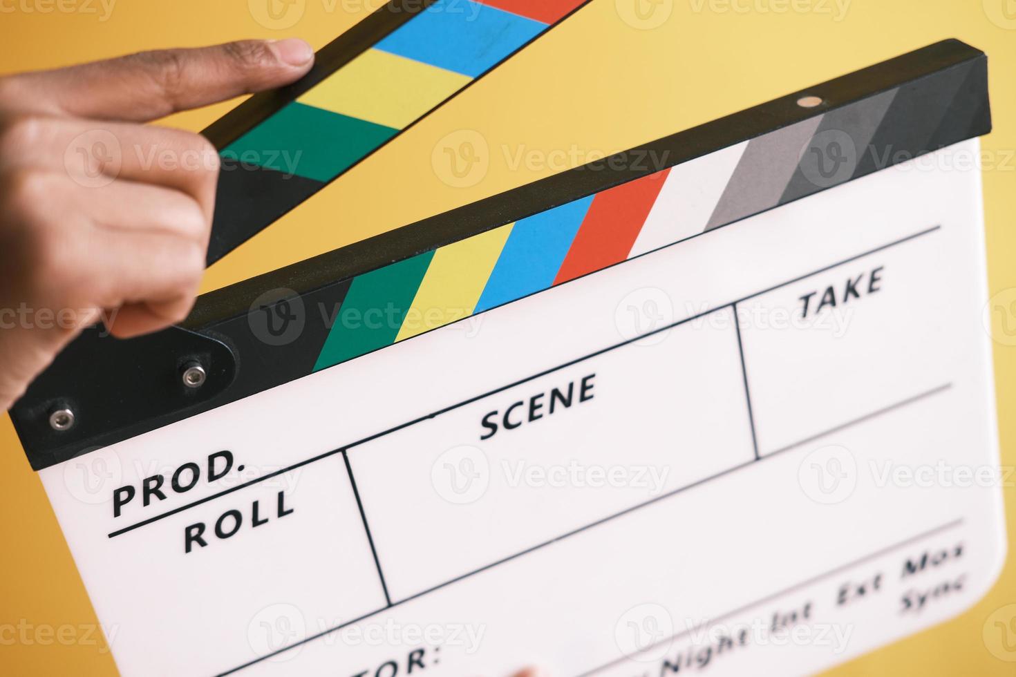 sosteniendo el tablero de la chapaleta de la película contra la pared blanca foto