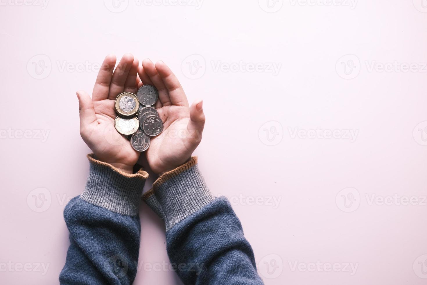 child girl holding saving coins on hand on light purple background photo