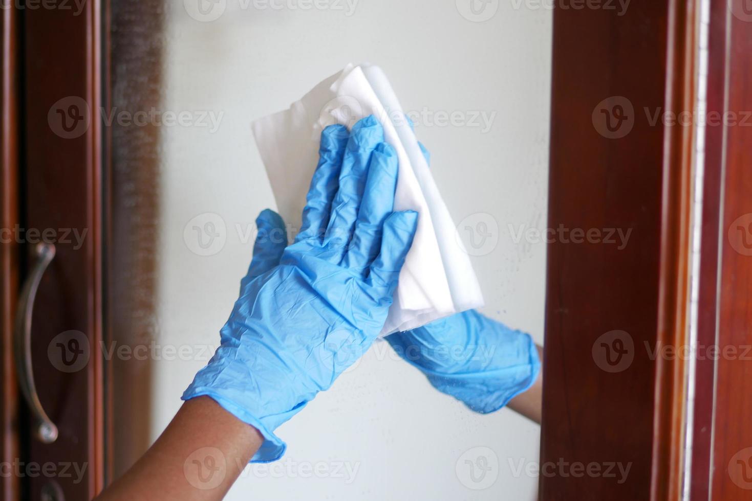close up of person hand in gloves cleaning glass photo