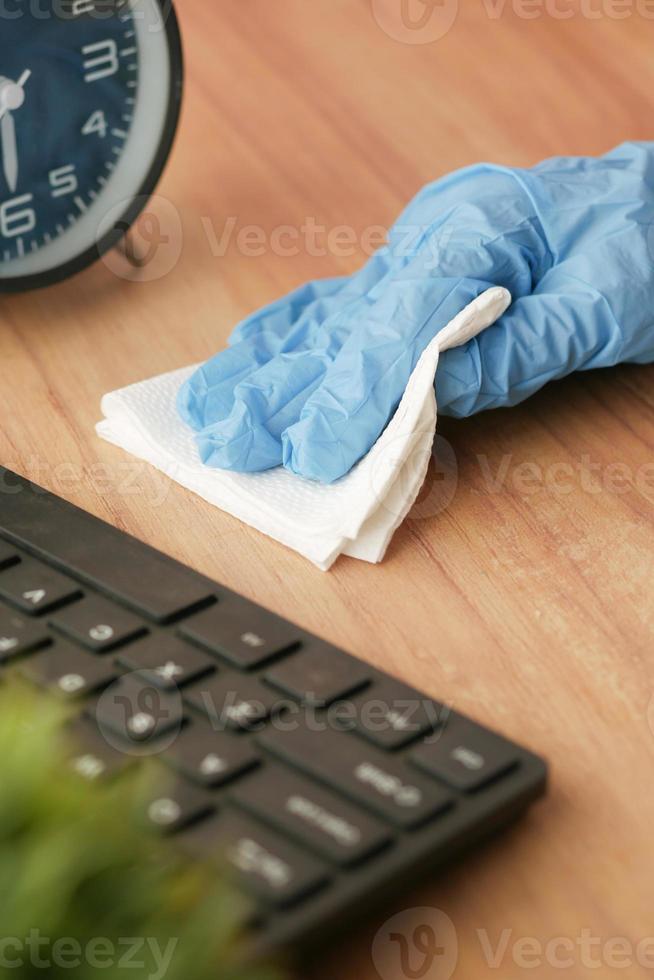 Mano en guantes de goma azul sosteniendo la mesa de limpieza de botellas de spray foto