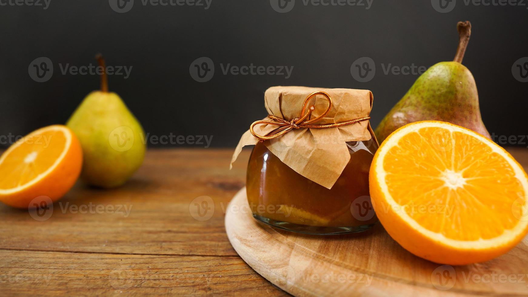 Glass jar of homemade pear and orange jam with fresh fruits on the table photo